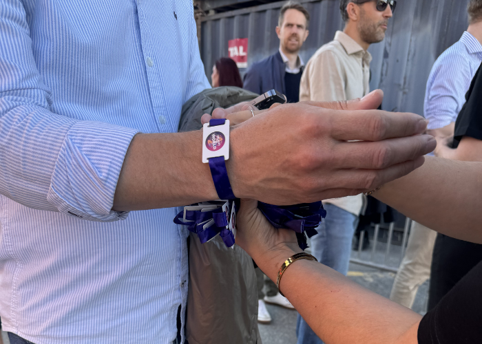 A woven purple wristband with an RFID chip being fitted for event access control.