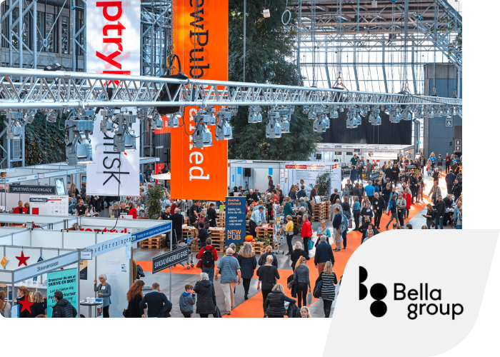 A busy trade fair with many visitors between the stands under a large glass roof. The Bellagroup logo is inset in the corner.